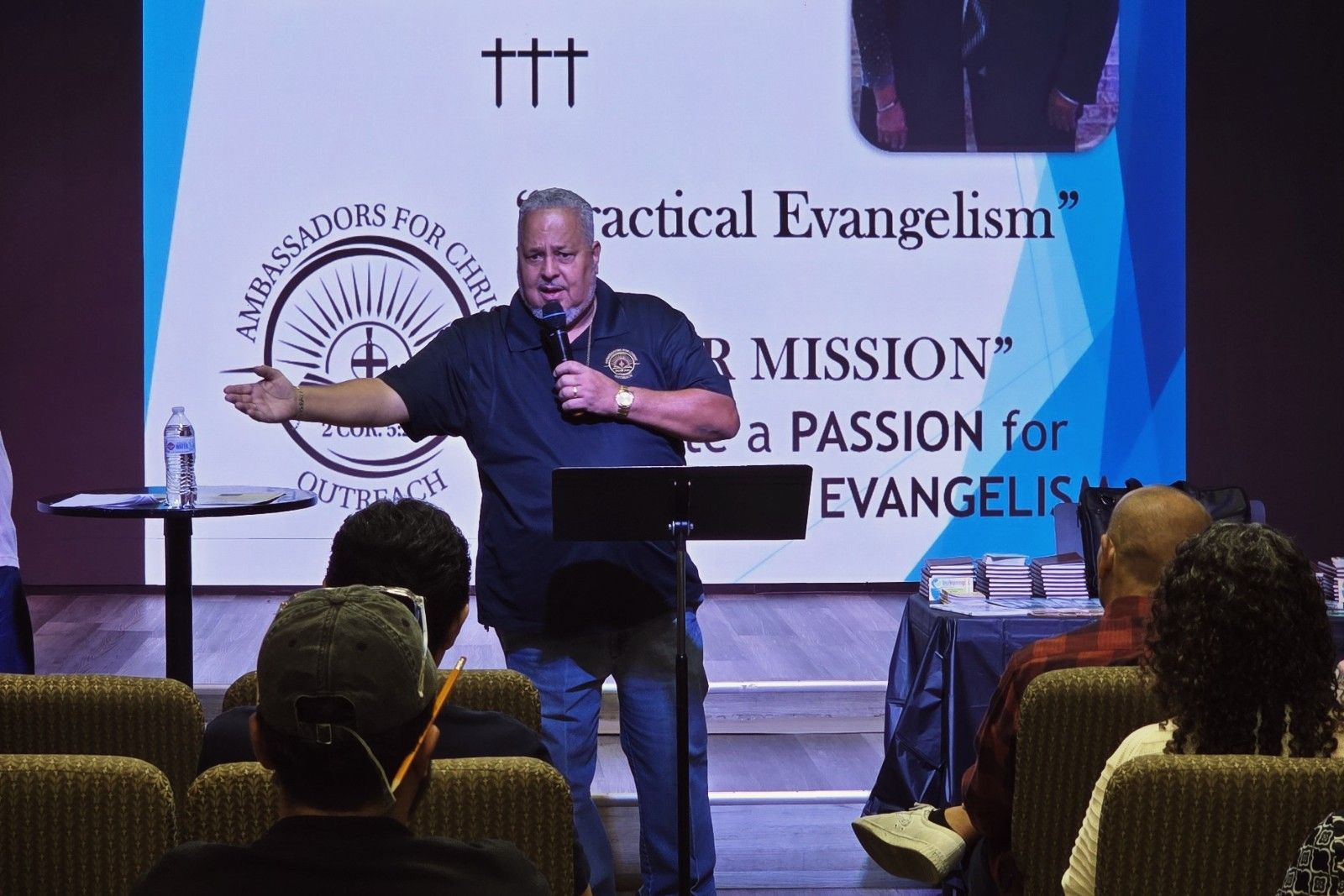 Rick Fernandez teaches a Practical Evangelism training session beside a projected AFCO 5:20 slide.