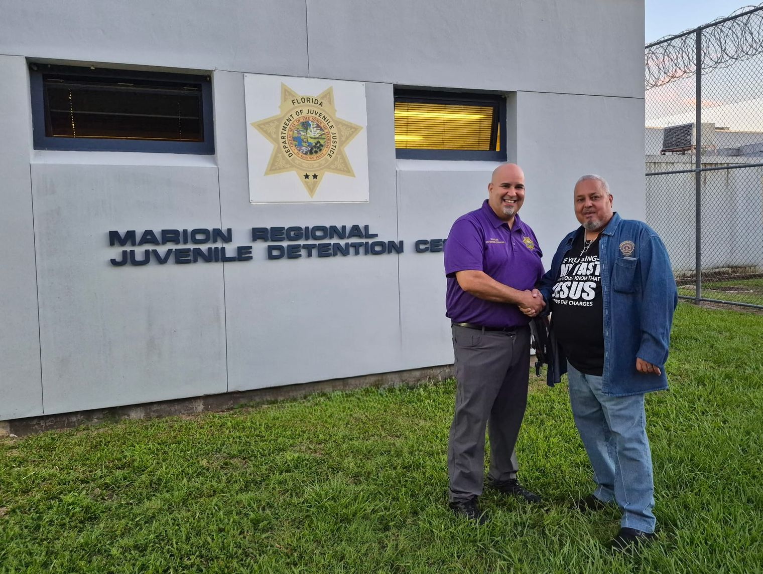 Evangelist Rick Fernandez and the facility chaplain shake hands outside the Marion Regional Juvenile Detention Center at sunset.