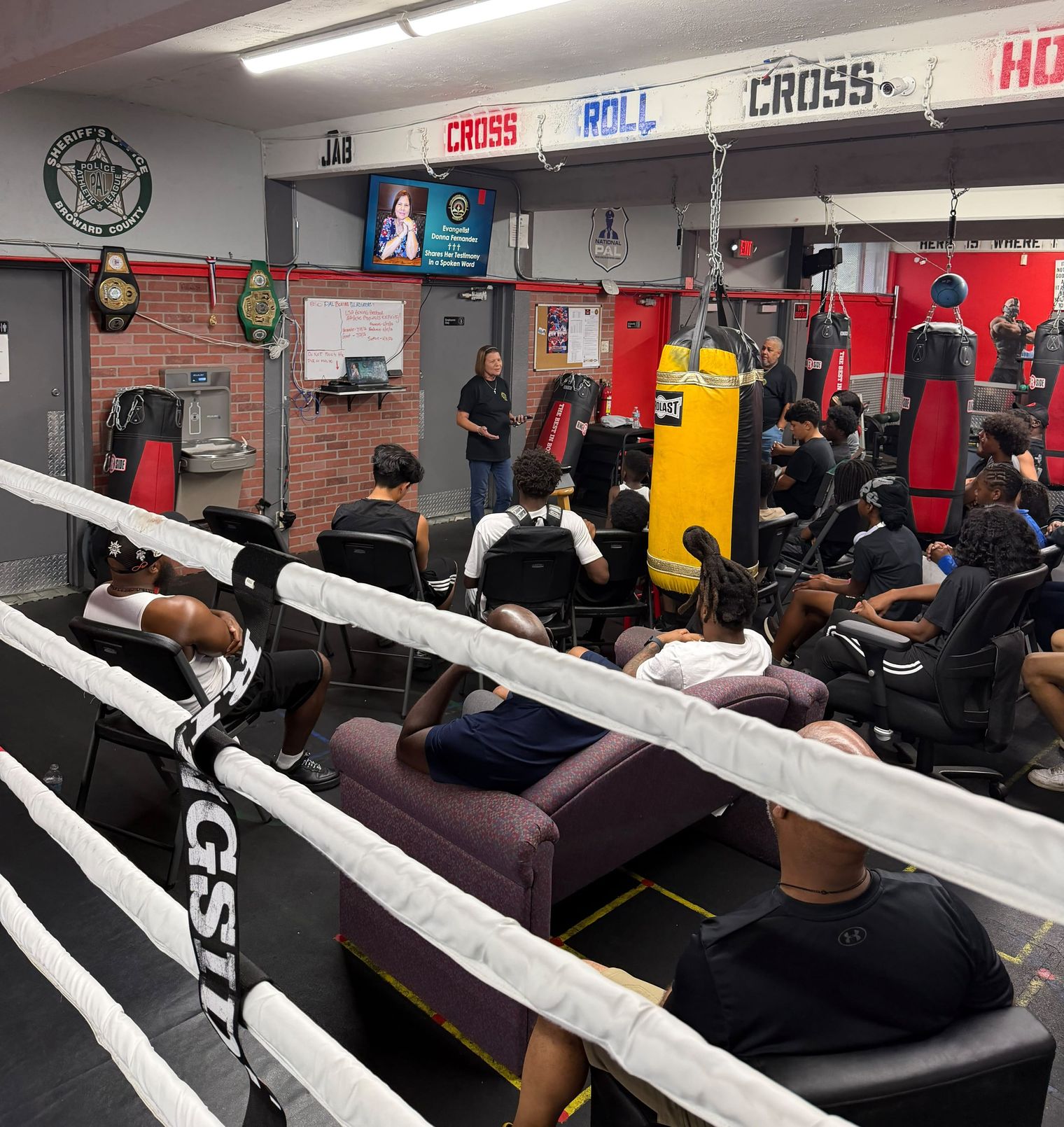 Seen through the ring ropes, Donna Fernandez speaks to the young people gathered among the heavy bags.