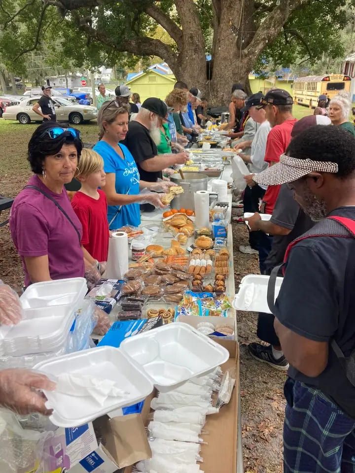 Volunteers serve plates along the food line at the park feeding.